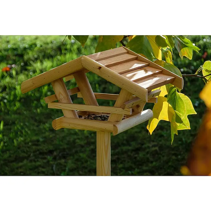 Dobar Vogelhaus Bernie Bernstein - 44 x 44 x 101 cm, Holz, Braun - Nahaufnahme eines hölzernen Vogelhauses auf einem Pfosten im Garten, umgeben von grüner Vegetation und Blättern.