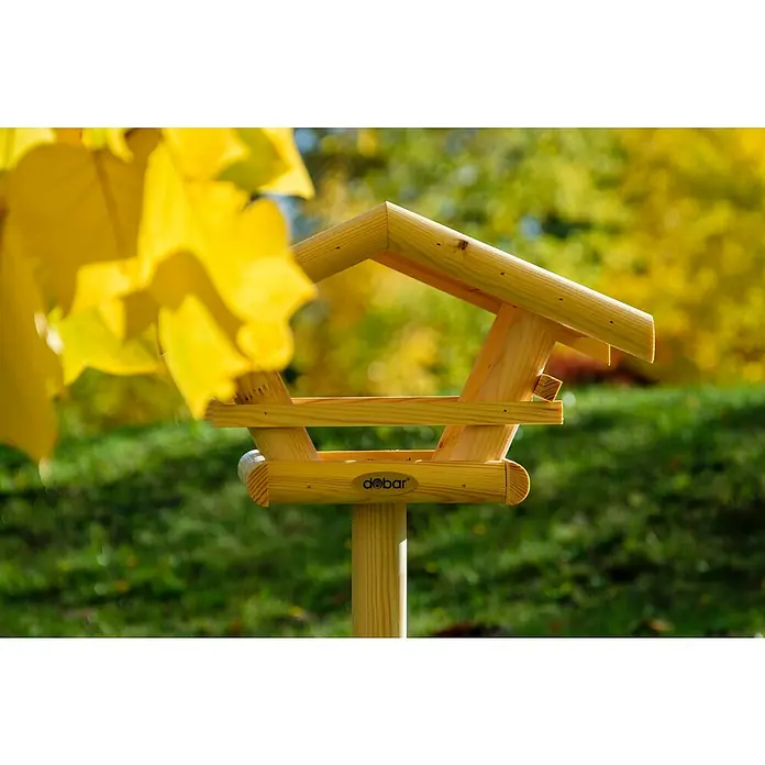 Dobar Vogelhaus Bernie Bernstein - 44 x 44 x 101 cm, Holz, Braun - Detailaufnahme eines Holz-Vogelhauses der Marke dobar vor einem grünen Hintergrund. Das Vogelhaus ist von gelben Blättern umgeben.
