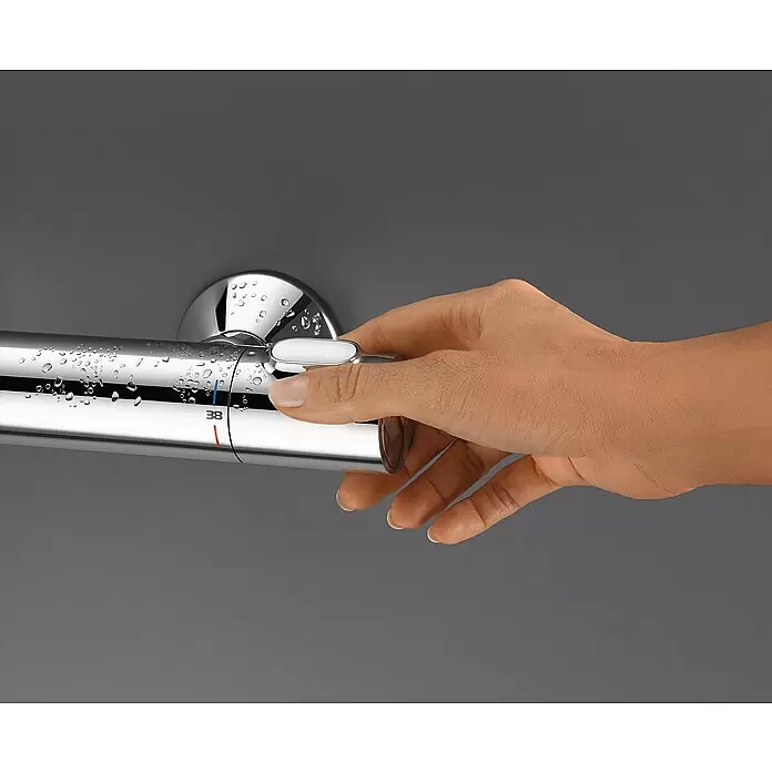 Grohe Brausethermostat Precision Flow - Chrom - Hand betätigt einen verchromten Duschthermostat mit Wassertropfen und sichtbarer 38°-Markierung.