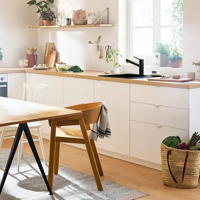 Hansgrohe Grifo de cocina Zesis - Negro, Mate, Giratoria - Cocina luminosa con fregadero y grifo negros. La luz natural enfatiza el diseño moderno y los ingredientes frescos.