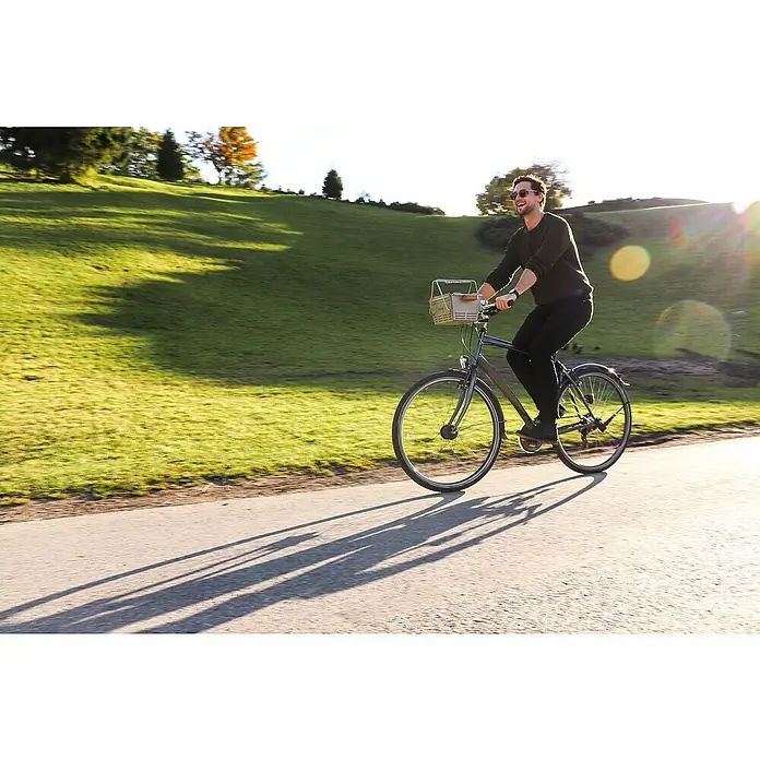 Knister Fahrradhalterung - L x B x H: 13 x 13 x 10 cm, Passend für: Knister Grill Modelle / Handelsübliche Fahrradlenker - Ein stilvolles Fahrrad mit Korb, gefahren von einem Mann in lässiger Kleidung auf einer sonnigen Straße.