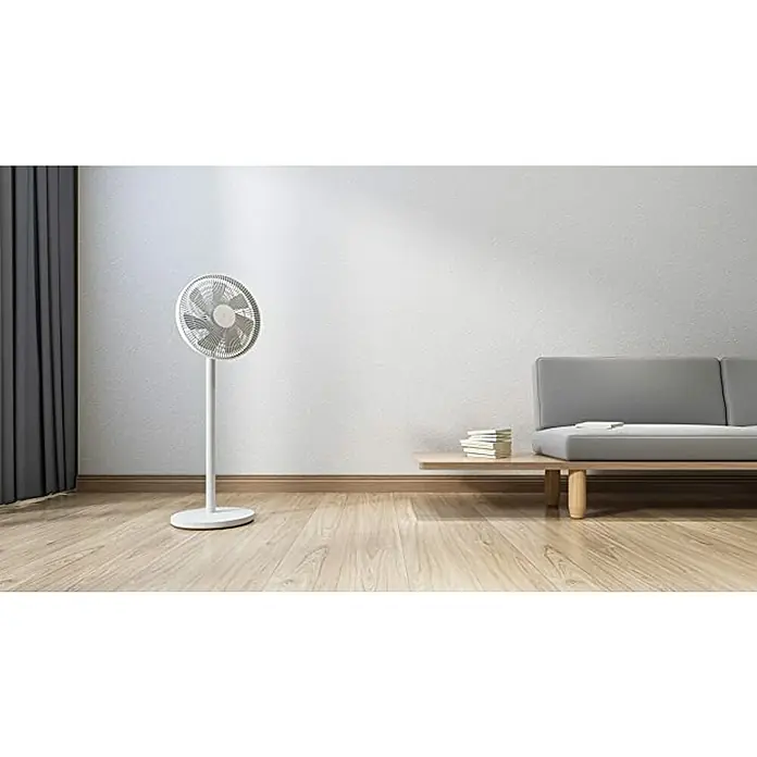 Xiaomi Ventilador de pie Mi Smart Standing Fan 1C / 2 Lite - Blanco, 90 cm - Un espacio minimalista con un ventilador de pie blanco que brinda una brisa suave, complementado con un sofá gris claro y cortinas oscuras.
