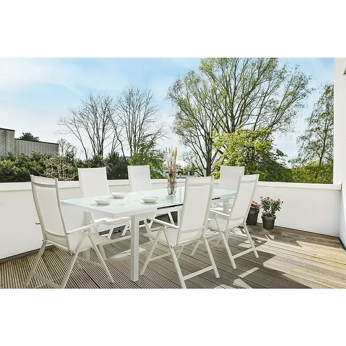 Sunfun Hannah Sillón de posiciones - 60 x 67 x 110 cm, Blanco, Abatible - Una mesa de comedor con sillas blancas en una terraza. La mesa está decorada con platos y flores, ideal para comer al aire libre.