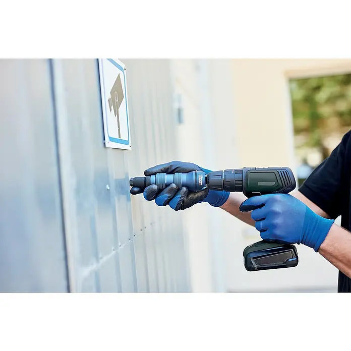 Rapid Nietmutter-Adapter RP160 - Geeignet für: Akkuschrauber/Bohrmaschinen - Ein Mann mit blauen Handschuhen nietet mit einem Rapid-Akku-Blindnietvorsatz ein Blech. Perfekt für schnelle, präzise Nietarbeiten.