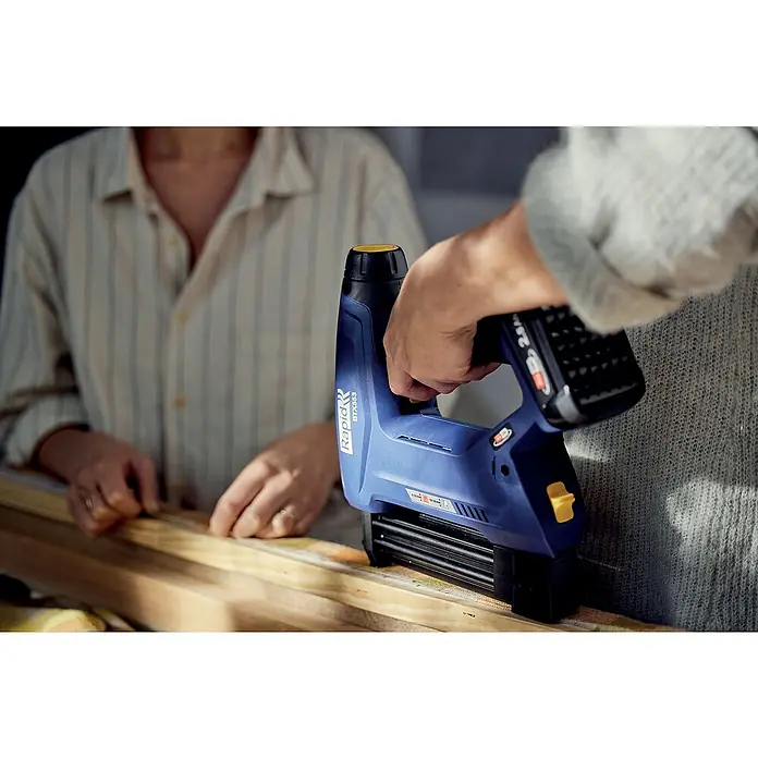Rapid Power for All 18V Akku-Tacker BTX553 - 18 V, Ohne Akku, Klammertiefe: 8 mm - 20 mm - Eine Nahaufnahme eines blauen Rapid BTX653 Akku-Nagler, der auf Holz verwendet wird, ideal für Heimwerker- und Bauprojekte.