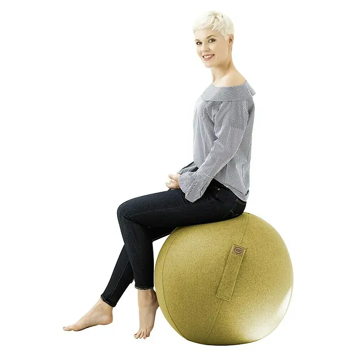 Sitting Ball Gymnastikball Felt - Senf, Durchmesser: 65 cm, 100 % Polyester - Frau sitzt auf einem gepolsterten Gymnastikball in Olivgrün, der eine praktische Trageschlaufe hat. Für eine aufrechte Körperhaltung.