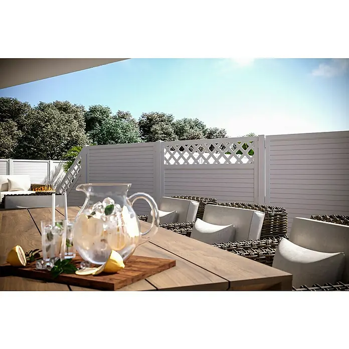 T & J Lightline Sichtschutzelement - 90 x 180 cm, Mit Rankgitter, Weiß, Abschlusselement - Ein erfrischender Krug mit Zitronenlimonade auf einem Holztisch, umgeben von stilvollen Rattanmöbeln und einer weißen Zaunlandschaft im Hintergrund.