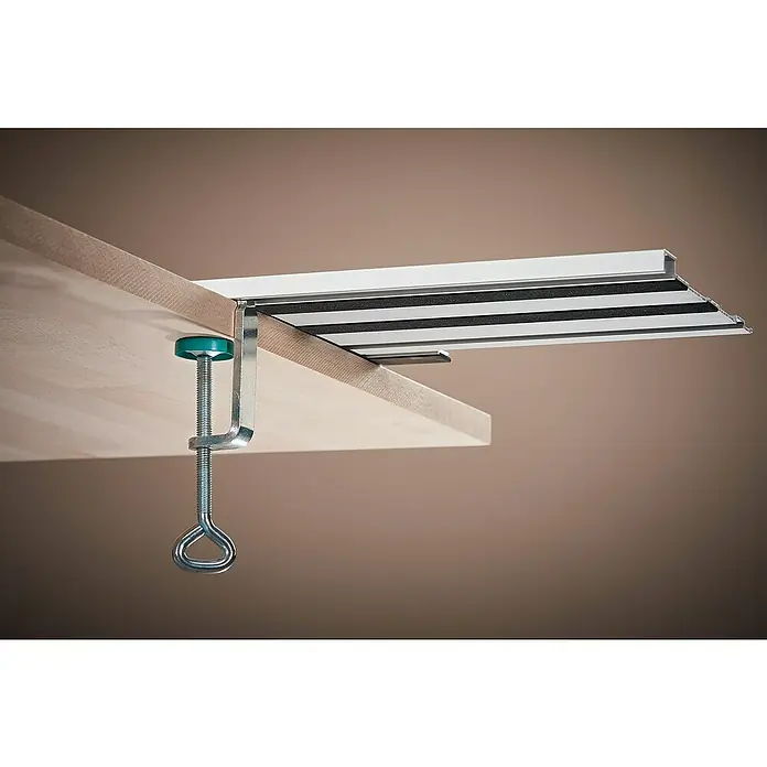 Wolfcraft Guía de carril FKS 145 - L x An x Al: 145 cm x 19 cm x 1,2 mm, Aluminio - Vista detallada de un soporte de mesa con abrazadera que sujeta un tablero de madera. El soporte es de aluminio y goma negra.