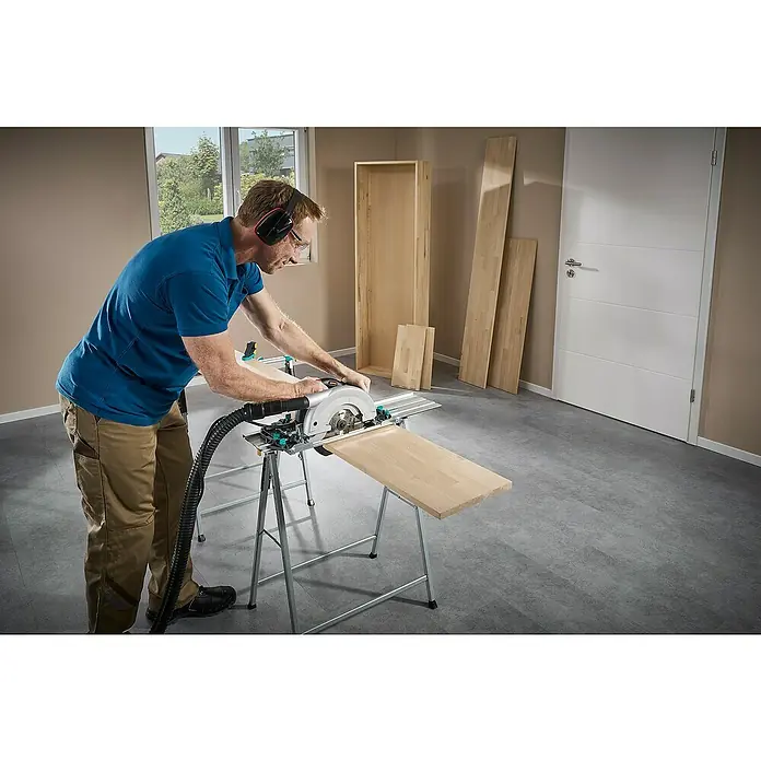 Wolfcraft Guía de carril FKS 145 - L x An x Al: 145 cm x 19 cm x 1,2 mm, Aluminio - Un hombre usa una sierra Wolfcraft en un banco de trabajo para cortar una pieza de madera. Se toman precauciones de seguridad como gafas y auriculares.