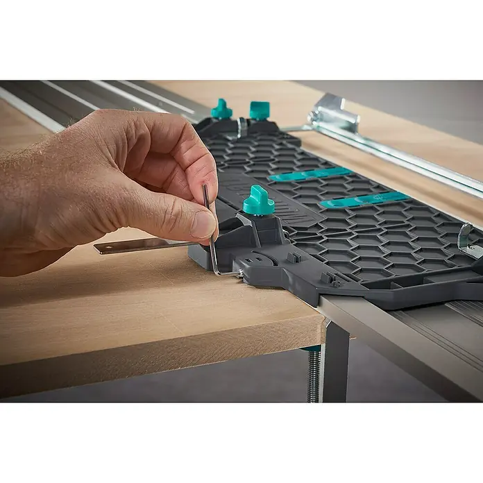 Wolfcraft Guía de carril FKS 145 - L x An x Al: 145 cm x 19 cm x 1,2 mm, Aluminio - Primer plano de una persona ajustando una regla de corte Wolfcraft con una llave Allen.