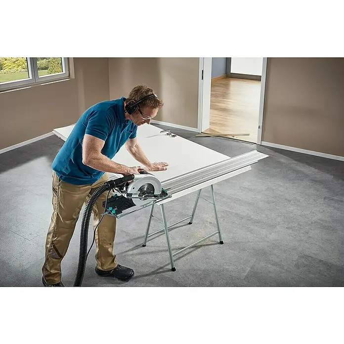 Wolfcraft Guía de carril FKS 145 - L x An x Al: 145 cm x 19 cm x 1,2 mm, Aluminio - Un hombre que usa una sierra Wolfcraft para cortar una puerta colocada sobre un caballete Wolfcraft para modificar su tamaño.