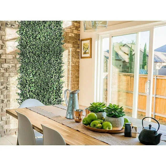 Faura Jardín vertical Irolia - Plástico, L x An: 50 x 50 cm - Decoración de mesa con plantas verdes, jarra y tetera sobre una mesa de madera, contra una pared de ladrillos y puertas correderas de cristal.