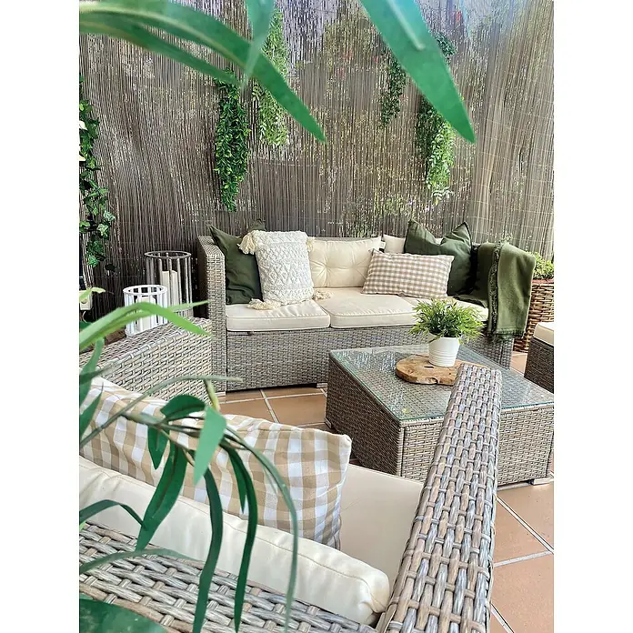 Nortene Ocultación de mimbre Fency Wick - L x Al: 3 x 2 m, Plástico, Marrón castaño - Un acogedor salón al aire libre con sofás de ratán gris, cojines beige y una mesa, complementado con plantas decorativas y una pared de madera.