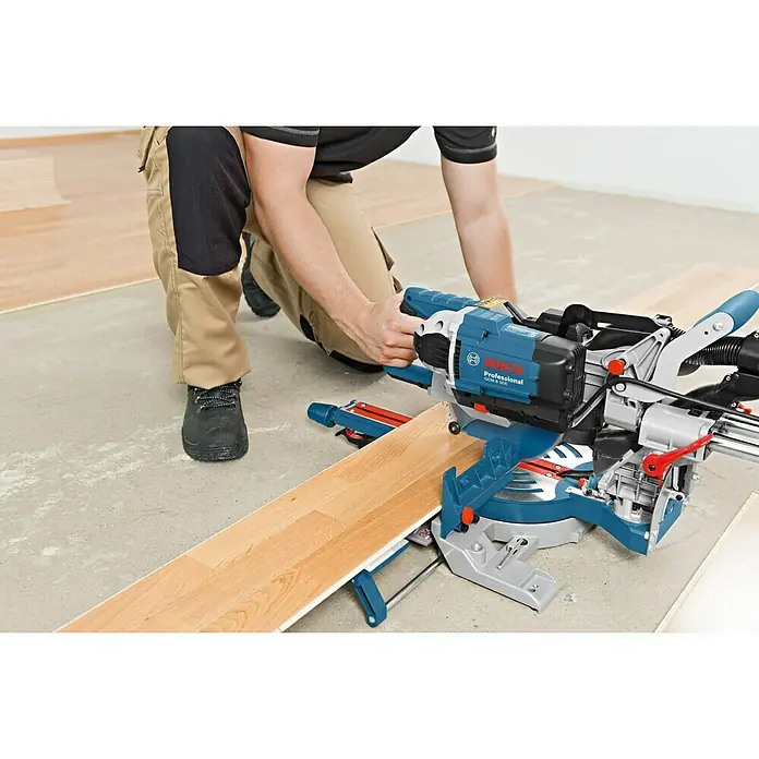 Bosch Professional Paneelsäge GCM 8 SDE - 1.600 W, Durchmesser Sägeblatt: 216 mm - Nahaufnahme der Bosch Professional GCM 8 SJL Kapp- und Gehrungssäge beim Schneiden eines Holzstücks, bedient von einer Person in Arbeitskleidung.