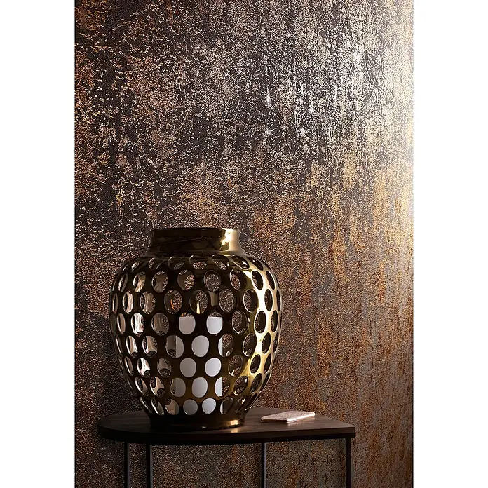 Marburg Avalon Vliestapete - Kupfer, Betonoptik, 10,05 x 0,53 m - Dekorative goldene Laterne mit Lochmuster und Kerze im Inneren, auf einem kleinen Tisch platziert.