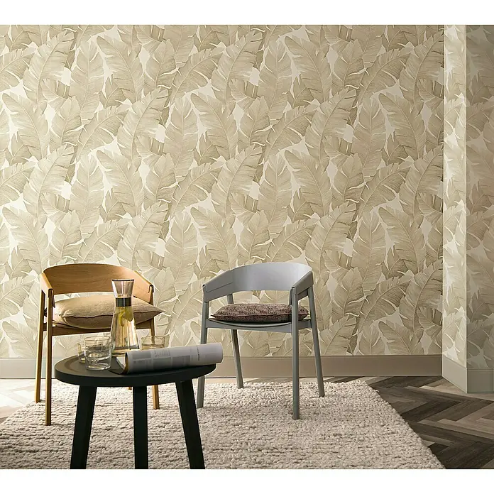 Marburg Avalon Vliestapete - Beige, Floral, 10,05 x 0,53 m - Eine stilvolle Interieur-Szene mit einem dekorativen Blattmuster an der Wand und Sitzmöbeln, die eine entspannende Atmosphäre schaffen.