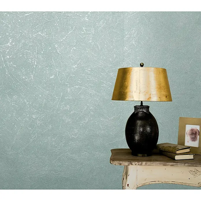 Marburg Vintage Deluxe Vliestapete - Grün-Pearl, Uni, 10,05 x 0,53 m - Eine elegante schwarze Lampe mit goldenem Schirm steht auf einem Tisch und verleiht dem Raum eine stilvolle Note.