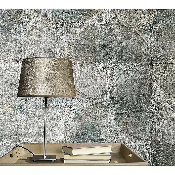 Marburg Vintage Deluxe Vliestapete - Grau-Anthrazit, Grafisch, 10,05 x 0,53 m - Tischlampe mit strukturiertem, beigem Schlangenleder-Lampenschirm und silbernem Fuß, auf einem Holztablett mit Büchern vor gemusterter Tapete.