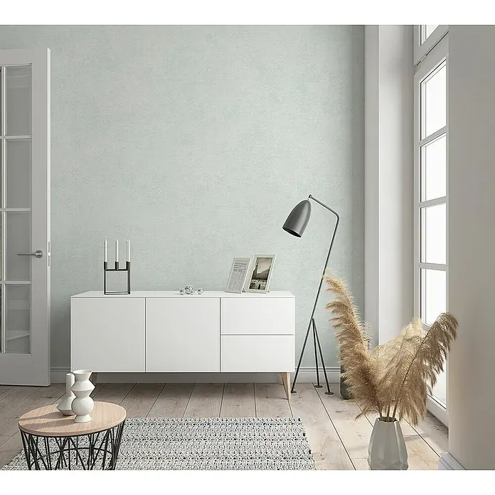Marburg Shades Vliestapete - Weißgrau, Uni, 10,05 x 0,53 m - Ein modernes Wohnzimmer mit einem weißen Sideboard, einer Stehlampe und dekorativen Elementen, die eine stilvolle Atmosphäre schaffen.