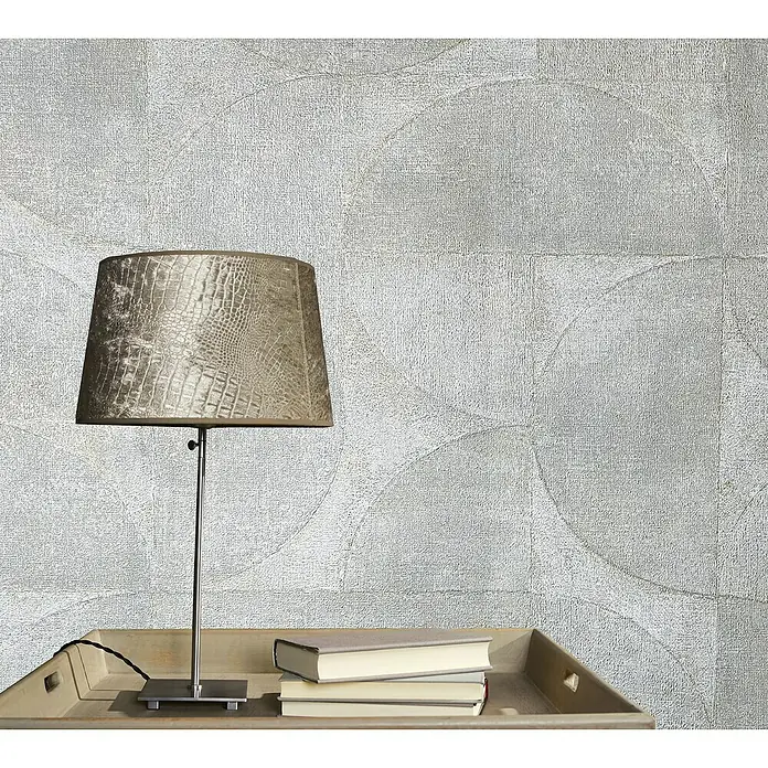 Marburg Vintage Deluxe Vliestapete - Pearl, Grafisch, 10,05 x 0,53 m - Elegante Tischleuchte mit Schirm in Kroko-Optik, platziert auf einem Holztablett mit Büchern vor einer dezent gemusterten Wand.