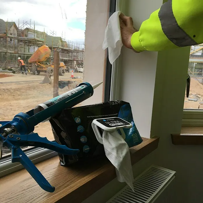 Feuchte Reinigungstücher Ultra Grime - 100 Stk. - Ein Bauarbeiter reinigt mit einem Ultra Grime Reinigungstuch ein Fenster auf einer Baustelle.