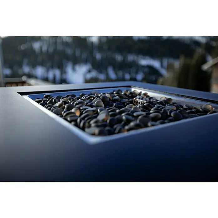 MWH Feuerstelle Palermo - 55 x 55 x 79 cm, Aluminium, Schwarz - Nahaufnahme einer schwarzen Feuerstelle mit Steinen und einem Metalleinsatz, die einen modernen und stilvollen Außenbereich betont.