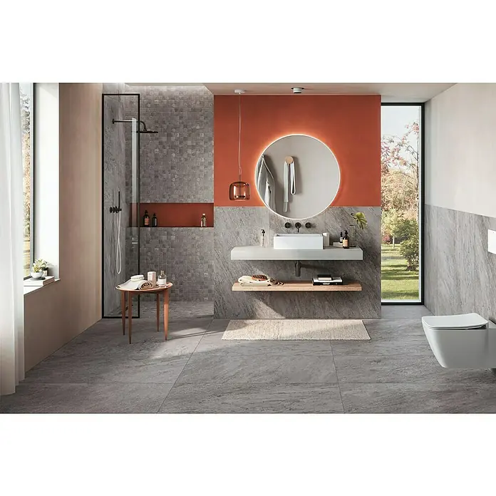 Corso Italia Feinsteinzeugfliese Regent - 60 x 120 mm, Matt - Elegantes Badezimmerdesign mit grauem Fliesenboden, einem runden Spiegel und modernen Armaturen für ein stilvolles Ambiente.