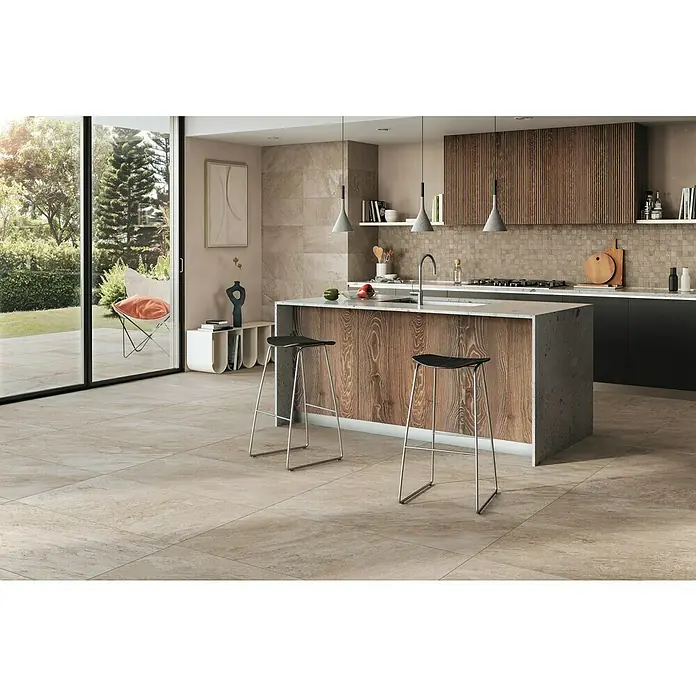 Corso Italia Feinsteinzeugfliese Regent Ivory - 30 x 60 cm, Beige/Braun, Matt - Innenaufnahme einer modernen Küche mit Fliesenboden, einer Kochinsel und Barhockern. Hängelampen erhellen den Raum.