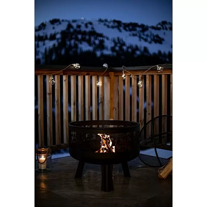 Buschbeck Feuerschale Leaves - Durchmesser: 63 cm, Stahl - Dunkle Metall-Feuerschale mit brennendem Feuer, die nachts auf einer Terrasse eine gemütliche Atmosphäre schafft.