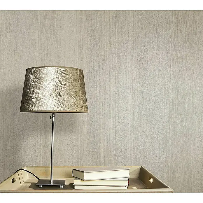 Marburg Vintage Deluxe Vliestapete - Pearl, Streifen, 10,05 x 0,53 m - Nahaufnahme einer Lampe mit Lampenschirm im Kroko-Design auf einem Tisch mit Büchern, die ein Ambiente von Eleganz und Stil vermittelt.