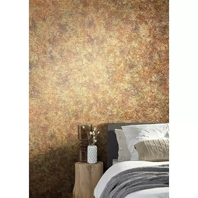 Marburg Natural Opulence Vliestapete Struktur I - Gold, Betonoptik, 10,05 x 0,7 m - Strukturierte goldbraune Tapete mit gealtertem, metallischem Aussehen hinter einem Bett.
