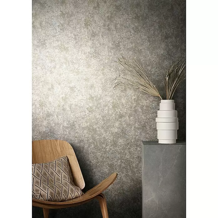 Marburg Natural Opulence Vliestapete Struktur I - Braun-Rot, Betonoptik, 10,05 x 0,7 m - Strukturierte Wand in Erdtönen, mit einem Holzstuhl und einer weißen Vase.