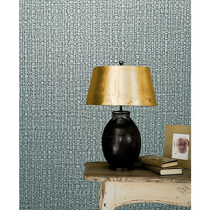 Marburg Vintage Deluxe Vliestapete Retro - Türkis-Silber, Uni, 10,05 x 0,53 m - Strukturierte, gewebte Wandverkleidung in Grüngrau, die eine Wand hinter einer Lampe und einem Beistelltisch schmückt.