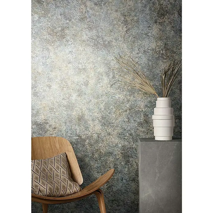 Marburg Natural Opulence Vliestapete Struktur I - Grau-Grün, Betonoptik, 10,05 x 0,7 m - Elegantes Interieur mit einem Sessel, einer Blumenvase und einer strukturierten Wand, das eine moderne und stilvolle Atmosphäre schafft.