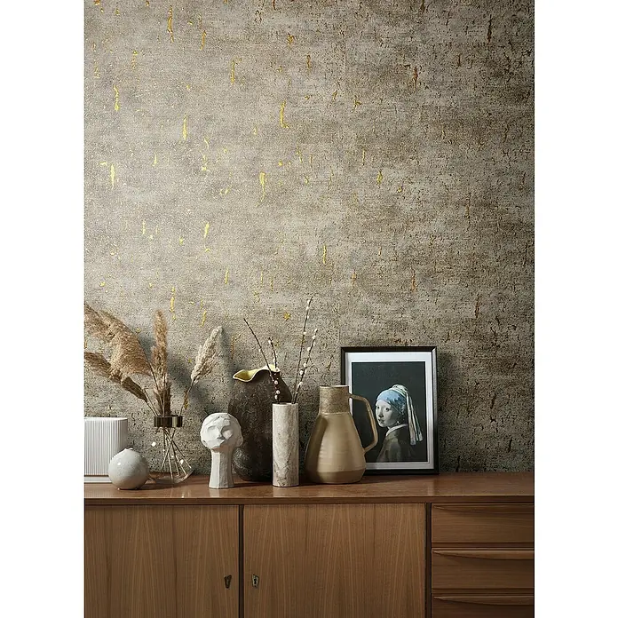 Marburg Natural Opulence Vliestapete - Braun-Grau, Betonoptik, 10,05 x 0,7 m - Einrichtungsfoto mit verschiedenen Vasen, einer Skulptur und einem gerahmten Bild auf einem Sideboard vor einer strukturierten Wand.