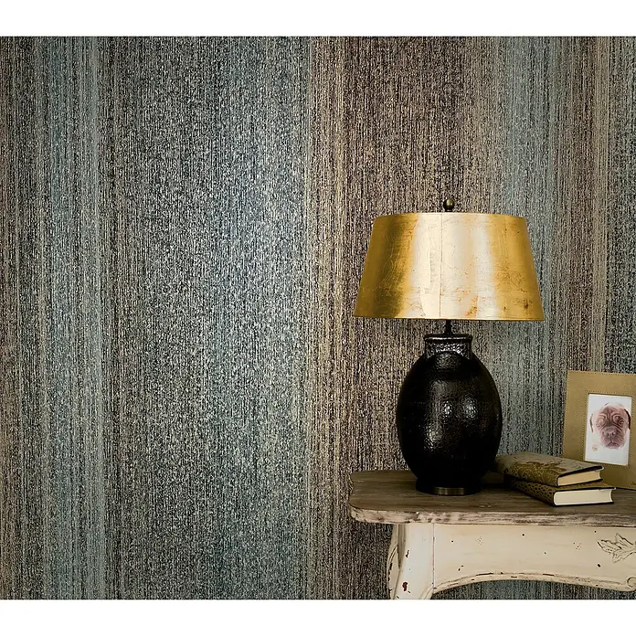 Marburg Vintage Deluxe Vliestapete - Gold-Anthrazit, Streifen, 10,05 x 0,53 m - Elegante Tischleuchte mit goldenem Schirm und dunklem Sockel auf einem Beistelltisch vor einer strukturierten Wand.