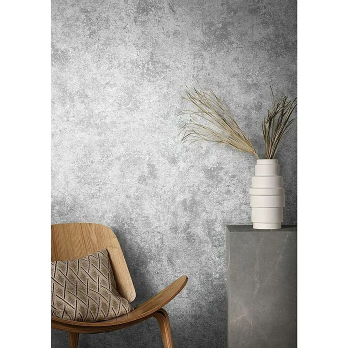 Marburg Natural Opulence Vliestapete Struktur I - Grau, Betonoptik, 10,05 x 0,7 m - Nahaufnahme einer stilvollen Einrichtung mit einem eleganten Stuhl, einer modernen Vase und einer strukturierten Wand.