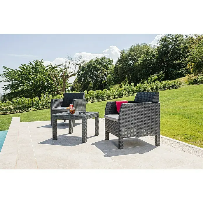 Toomax Loungemöbel-Set Matilde - Kunststoff, Schwarz, 3 -tlg. - Zwei graue Korbsessel und ein Tisch auf einer Terrasse mit Getränken und einer roten Decke, umgeben von Grün.