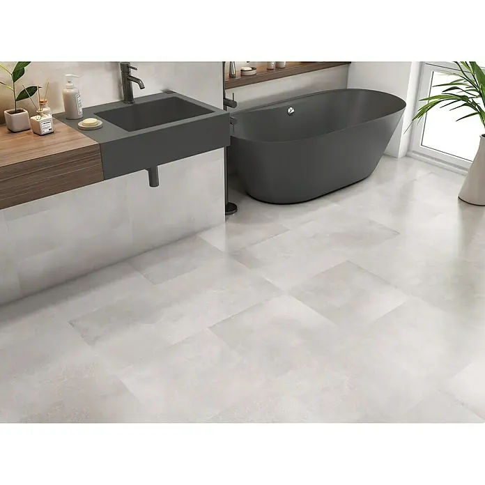 BHS Showroom Pavimento porcelánico Energy - 45 x 45 cm, Natural, Mate - Baño luminoso con bañera y lavabo grises. Las baldosas del suelo son cuadradas y gris claro.