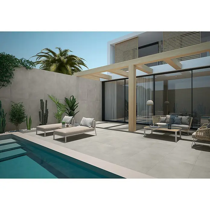 BHS Showroom Pavimento porcelánico Energy - 120 x 60 cm, Natural, Mate, Rectificado - Toma exterior con baldosas alrededor de una piscina, complementada con tumbonas y asientos, creando un espacio exterior sereno.