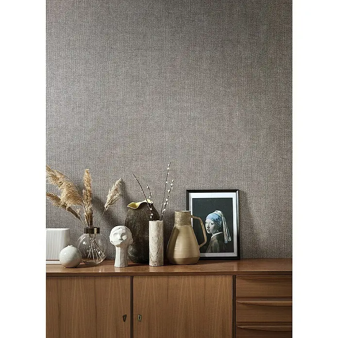 Marburg Natural Opulence Vliestapete - Rot-Braun, Uni, 10,05 x 0,7 m - Dekorative Gegenstände auf einem Holzschrank mit einem Bild des Mädchens mit dem Perlenohrring im Hintergrund.