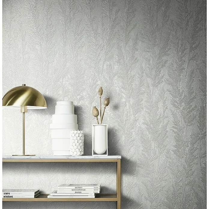 Marburg Natural Opulence Vliestapete Weiche Gräser - Weiß, Floral, 10,05 x 0,7 m - Nahaufnahme eines dekorierten Regals mit Büchern, einer Lampe und stilvollen Vasen vor einer eleganten, strukturierten Wand.