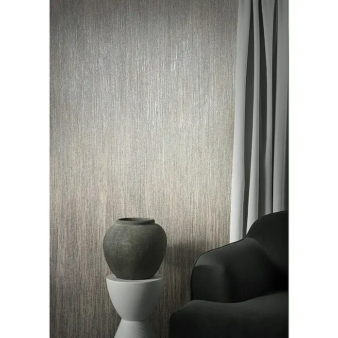 Marburg Natural Opulence Vliestapete - Greige, Streifen, 10,05 x 0,7 m - Elegantes Interieur mit einer strukturierten Tapete in Grau, einer dunklen Vase auf einem weißen Beistelltisch und einem stilvollen Sessel.