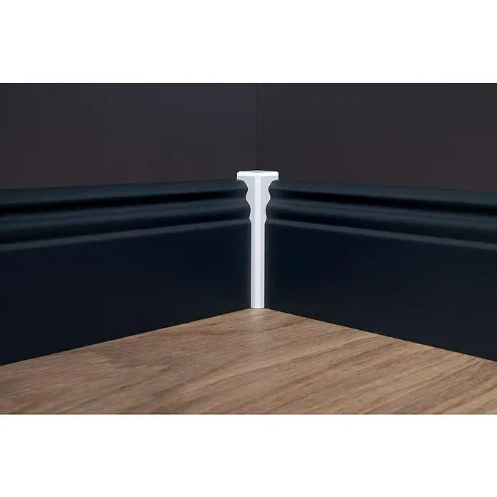 Sockelleiste - 240 cm x 16 mm x 80 mm, Fichte, Anthrazit, Lackiert - Detailaufnahme von dunkelblauem Sockelleisten-Eckstück, ergänzt durch einen eleganten weißen Eckverbinder, auf einem warmen Holzfußboden.