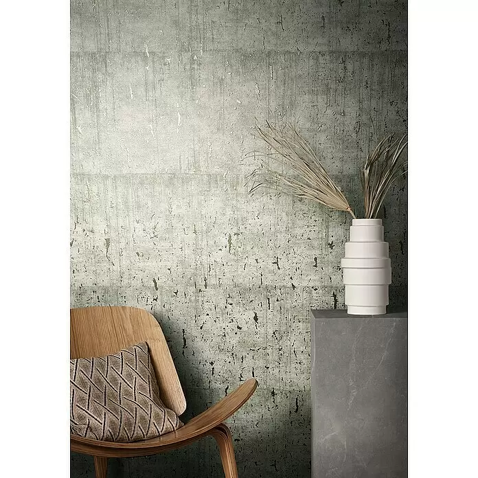 Marburg Natural Opulence Vliestapete - Helles Greige, Betonoptik, 10,05 x 0,7 m - Strukturierte grün-graue Tapete im Used-Look, die als moderne Kulisse für Holzstuhl und Dekoration dient.
