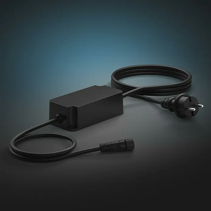 Philips Hue Netzteil Outdoor - Max. Leistung: 40 W, Schwarz, L x B x H: 13,2 x 6,5 x 4,1 cm - Schwarzes LED-Netzteil mit Kabel und Stecker auf dunklem Untergrund. Die Stromversorgung ist kompakt und für LED-Leuchten konzipiert.