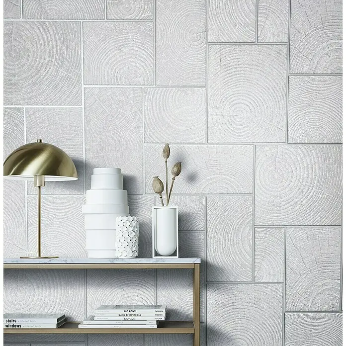 Marburg Natural Opulence Vliestapete - Weiß-Grau, Holzoptik, 10,05 x 0,7 m - Einrichtungsgegenstände auf einem stilvollen Tisch, vor einer Wand mit einem attraktiven, holzähnlichen Muster, das eine moderne Ästhetik erzeugt.