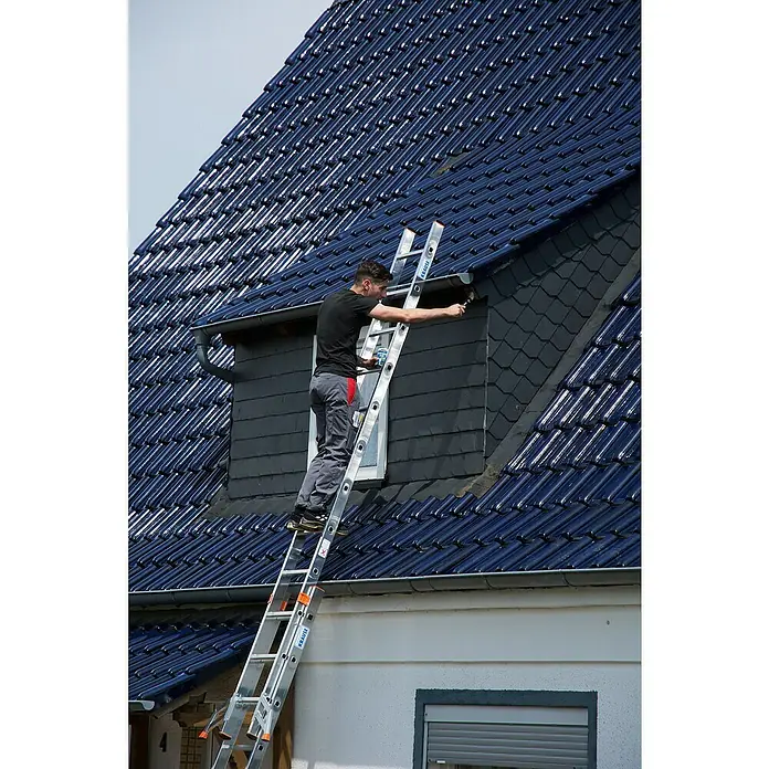 Krause Stabilo Seilzugleiter - Anzahl Tritte: 42 Stk., Arbeitshöhe: 9,75 m, Aluminium - Mann auf einer Leiter, der eine Dachgaube streicht. Die Leiter der Marke Krause steht an der Hauswand.