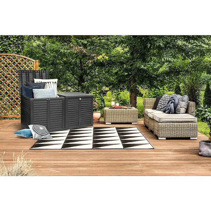 Jelenia Plast Garten-Aufbewahrungsbox XXL - L x B x H: 155 x 66 x 80 cm, Kunststoff, Anthrazit - Eine graue Gartenbox mit offenem Deckel, gefüllt mit Kissen, steht auf einer Holzterrasse mit einem Outdoor-Teppich und Gartenmöbeln.