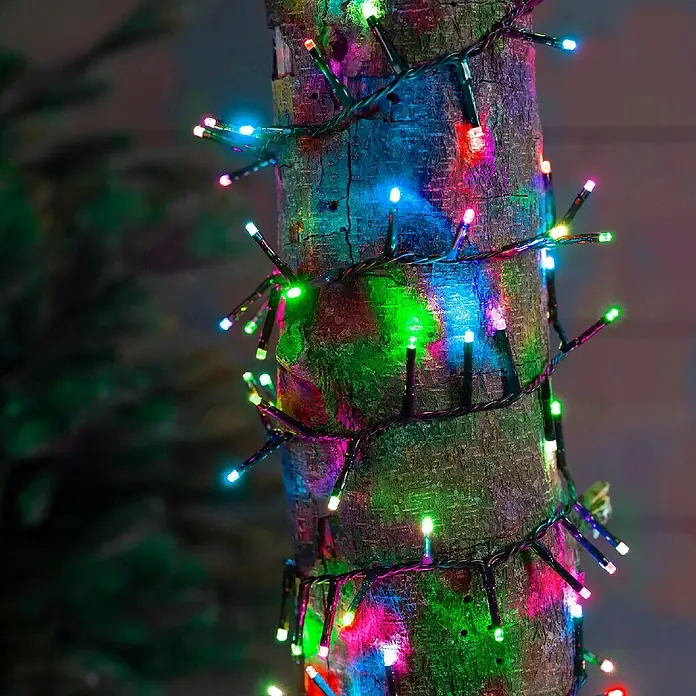 Guirnalda luminosa LED Compact - Para exterior, Color de luz: Multicolor, Número de bombillas: 500 ud., 11 m - Primer plano de una corteza de árbol envuelta en luces LED de colores creando un ambiente festivo.
